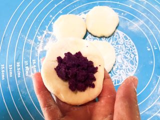 萌萌哒紫薯圣诞老人小馒头,取一个面团压扁，在面皮上面加入1勺紫薯泥