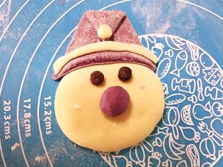 萌萌哒紫薯圣诞老人小馒头,开始组装，先把小白面球放在帽子上，把长条面压在帽子边缘，再加上两个眼睛，把鼻子放上去