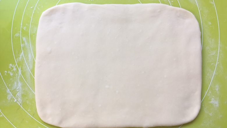 双色牛角酥,揉面垫上撒点干粉将白色面团擀成长方形，大小为小号保鲜袋的大小，之后包裹上油纸，装入保鲜袋入冰箱冷冻 