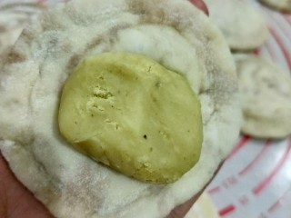 钳花绿豆包,取个剂子擀成中间厚周围薄的面皮，放入适量绿豆馅，包好并搓圆。