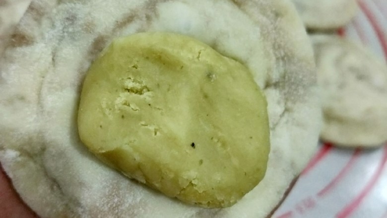 钳花绿豆包,取个剂子擀成中间厚周围薄的面皮，放入适量绿豆馅，包好并搓圆。