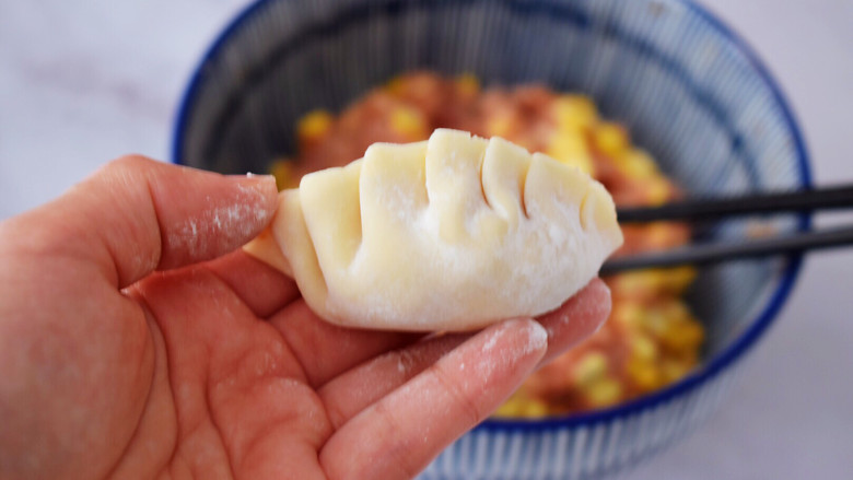 煎猪肉玉米饺子,先对折再把上面的饺子皮往左一折一折那样折好捏紧压实