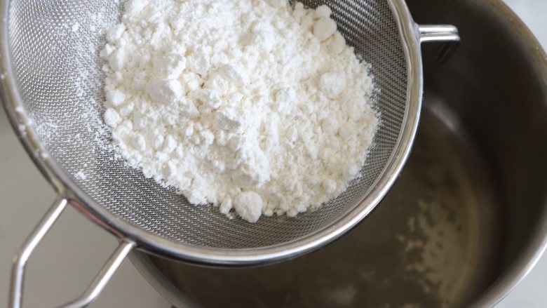 如棉花般口感的戚风蛋糕（烫面+水浴法）,倒入过筛的面粉，用刮刀快速的搅拌成细腻的烫面糊。