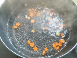 虾滑蝴蝶意面,小锅内加水煮开，放入胡萝卜花煮1分钟，捞出了放一旁备用