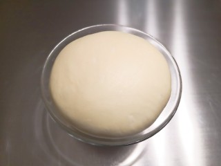 奶酪早餐包,揉到面团可以拉出手套膜，将揉好的面团放入容器里盖上保鲜膜，放入烤箱，在烤箱里放一碗热水增加湿度，帮助面团发酵，面团发至2.5倍大将面团拿出来