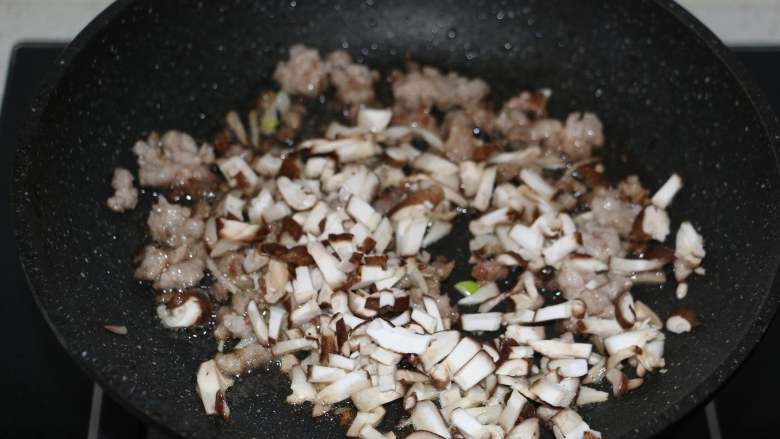 香菇糯米烧麦,翻炒至猪肉馅变白后，加入香菇丁翻炒。
