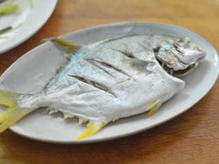 清蒸金鲳鱼,夹去姜丝和葱段，摆入干净的盘子里