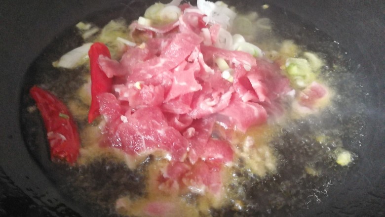家常菜#牛肉炒芹菜粉条#,锅中添油烧热后，把牛肉，朵椒。，放入到锅内炒熟。