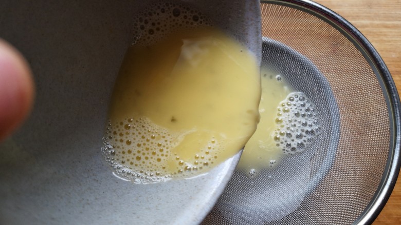 虾仁蒸蛋羹,将打好的蛋液过筛，将表面的泡泡滤出。这一步很关键哦，如果没捞滤出泡泡，那么有泡泡的地方蒸熟了是有很多小坑的，而且蛋液表面也不平整。