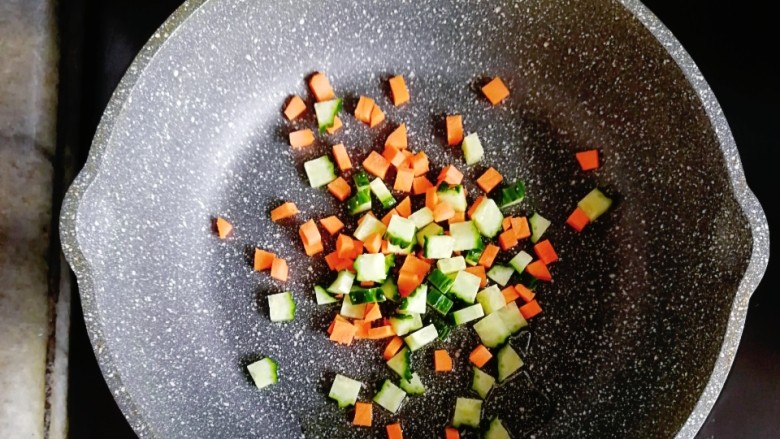 南瓜杂蔬炒三文鱼,锅内倒入少许油，放入胡萝卜和黄瓜丁翻炒至断生