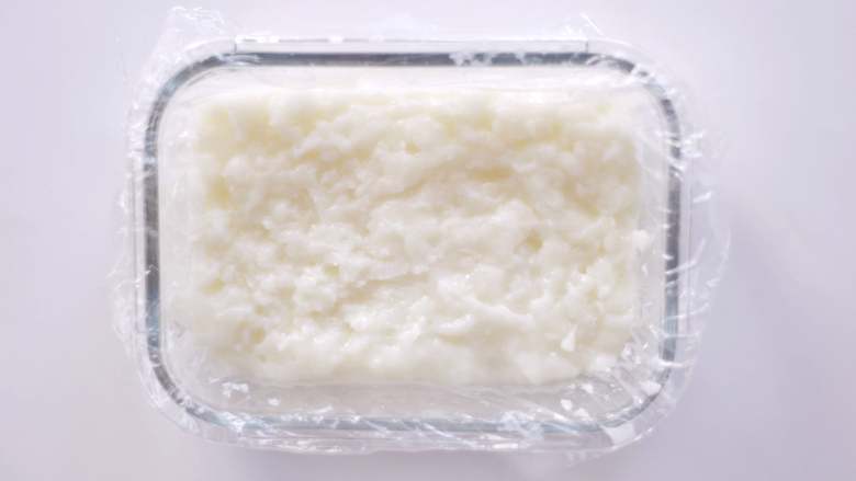 承味延世牛奶的椰蓉小奶冻 ,把奶糊倒入铺好保鲜膜的保鲜盒中，上下震几下让表面更平整。