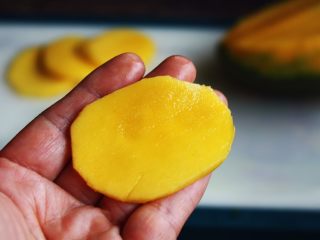 高颜值炫彩 紫薯芒果奶香饭团,将芒果切成椭圆型的薄片。