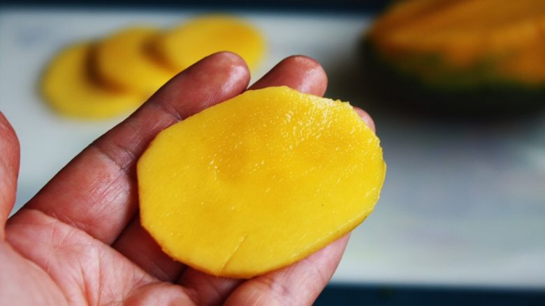 高颜值炫彩 紫薯芒果奶香饭团,将芒果切成椭圆型的薄片。