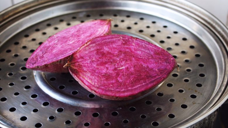 高颜值炫彩 紫薯芒果奶香饭团,紫薯切开放在蒸锅里蒸熟。