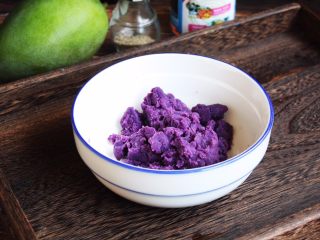 高颜值炫彩 紫薯芒果奶香饭团,将紫薯泥放在容器里，放入2勺的炼乳，搅拌均匀。