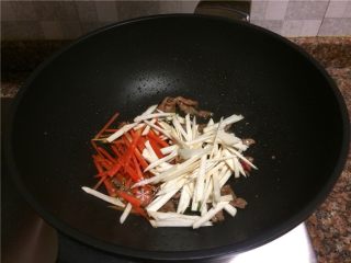 杂蔬牛肉炒乌冬面,放入胡萝卜和杏鲍菇翻炒30秒。