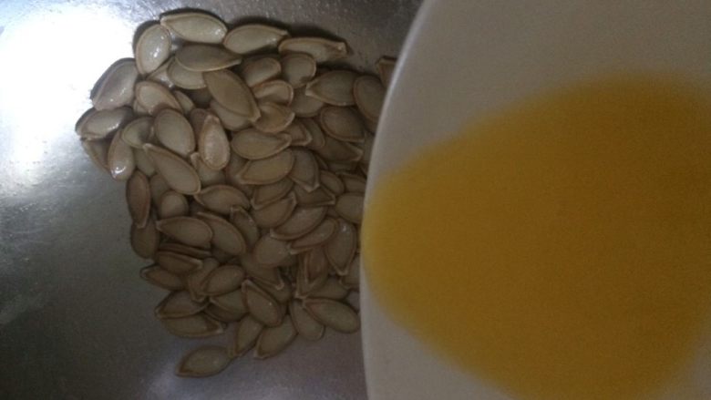 奶香南瓜籽,将融化的黄油倒入南瓜籽里，混合均匀；