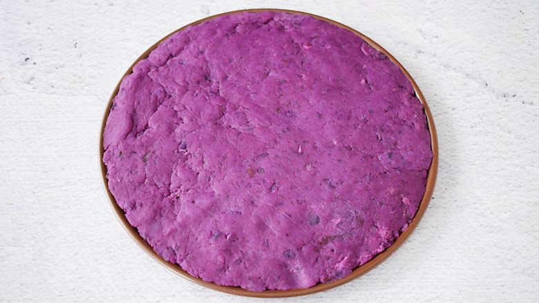 紫薯披萨,把紫薯泥均匀的铺上披萨盘上，用勺子压实了