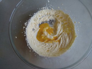 蔓越莓饼干,先不启动打蛋器电源，直接用打蛋头将糖粉和黄油混合一下，再开电源打发黄油至颜色变浅的状态，将全蛋液分三次倒入到黄油里。