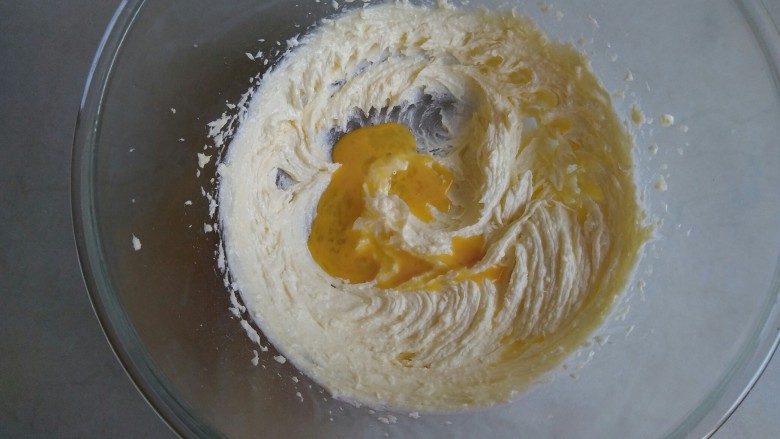 蔓越莓饼干,先不启动打蛋器电源，直接用打蛋头将糖粉和黄油混合一下，再开电源打发黄油至颜色变浅的状态，将全蛋液分三次倒入到黄油里。