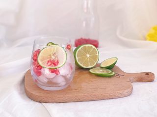 百变水果：粉色气泡水,杯子装好冰块 完整的石榴籽和切好的柠檬片