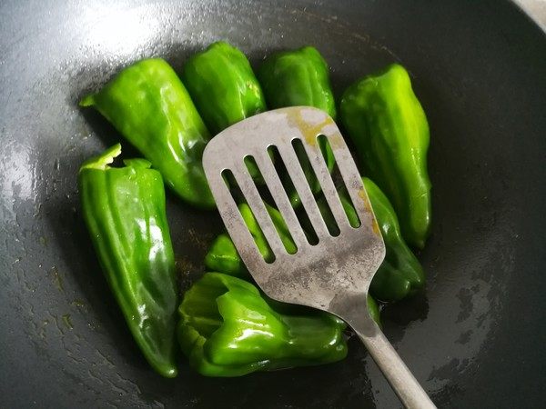 虎皮青椒,锅中倒入油烧六成热，放入青椒分散开，不要翻动，用锅铲按压青椒，改小火油煎。


