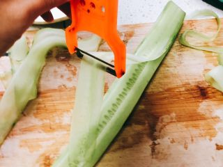 无油凉拌开胃黄瓜-可做减肥晚餐,用刮皮刀从黄瓜的一端向另一端刮过去，刮下一片片薄薄的长薄片。