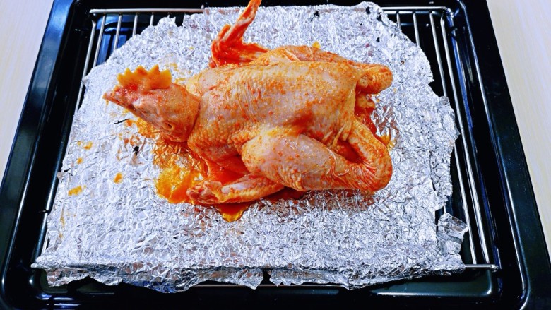 预热感恩节～这样烤出来的鸡实在太好吃了！,烤网垫上锡纸，再把腌制好的鸡放烤网上。（我把鸡做了个造型，在鸡脖子那里插了两根牙签，使鸡看起来像是趴在那里）