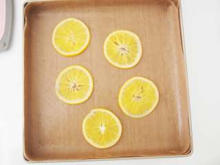 香橙蛋糕卷,烤盘中铺上高温油布，将橙子片摆放在中间