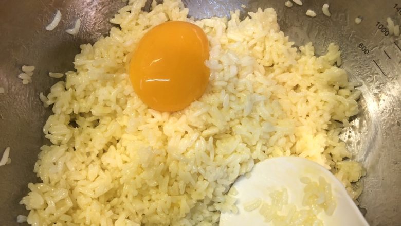 黄金腊肠火腿蛋炒饭,将分出来的两个鸡蛋黄倒入米饭中搅拌均匀后放一旁备用