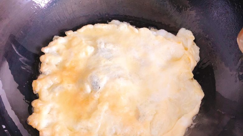 蛋包虾仁炒饭-宴请菜之主食,将蛋液倒入油锅煎成蛋饼，一面煎熟后翻面煎，直到两面都煎至金黄色。