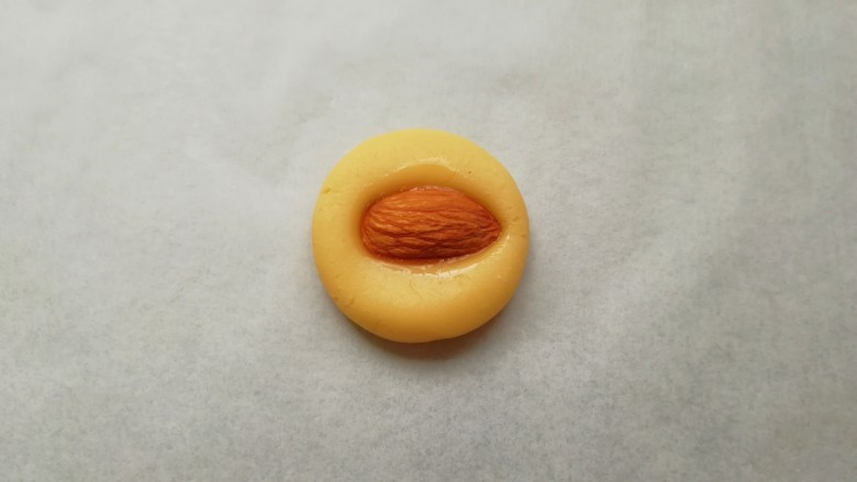黄油杏仁饼干,取一个搓好的小圆球压扁，再取一粒<a style='color:red;display:inline-block;' href='/shicai/ 113464'>大杏仁</a>，在装蛋液的小碗里沾上一点蛋液，放在压扁的面团中间，稍微用力压一下，一个杏仁饼干就做好了。