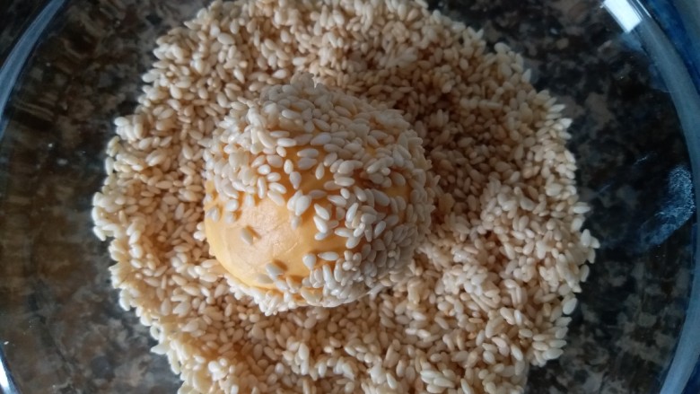 香糯南瓜饼,包好豆沙的南瓜球放进芝麻碗内，沾上芝麻