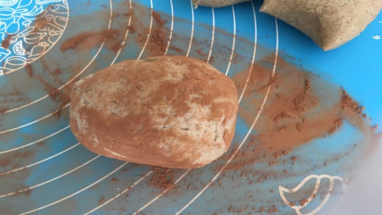 杂粮土豆餐包,把准备好的面团放在可可粉上轻轻滚动，使可可粉均匀的布满面团表面；
