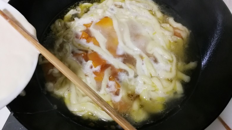 蒜香南瓜面疙瘩,筷子压着碗边的面团，压出比筷子细一点面条，将面条拨下锅，烧开转小火烧一分钟