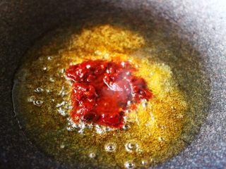 双椒爆鸡块,锅中倒入花生油烧热后放入郫县豆瓣酱进行煸炒。