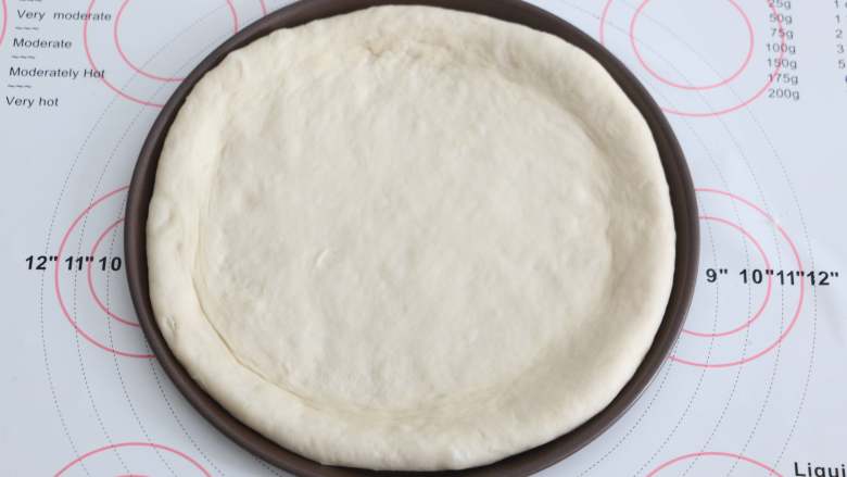 自制培根披萨,用擀面杖将面团擀成一个与披萨盘盘底一样大小的饼底，把饼皮铺进去。