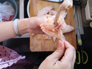 奥尔良鸡翅包饭,筋剪断后，将肉往下退，两根骨头很容易就掰离开了，如图所示。