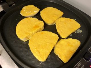 黄金小猪馒头片,电饼铛预热好之后，刷一层油，然后把鸡蛋馒头片放入煎制。