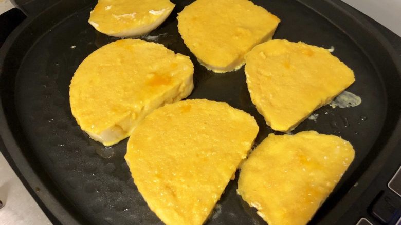 黄金小猪馒头片,电饼铛预热好之后，刷一层油，然后把鸡蛋馒头片放入煎制。