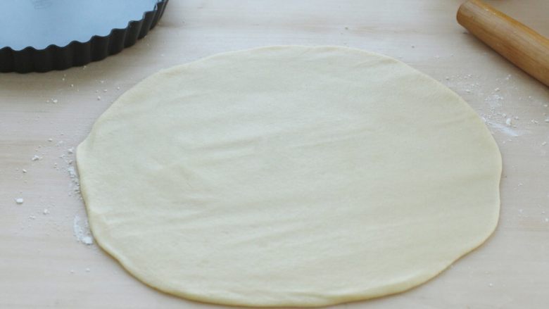 奶香南瓜派,在操作台上撒少许干面粉，取出冷藏的面团，用擀面杖擀成比派盘大一圈的饼皮