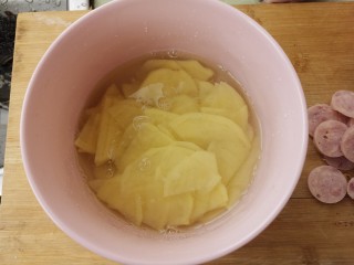 土豆片炒香肠,土豆片放碗里用水泡一下。