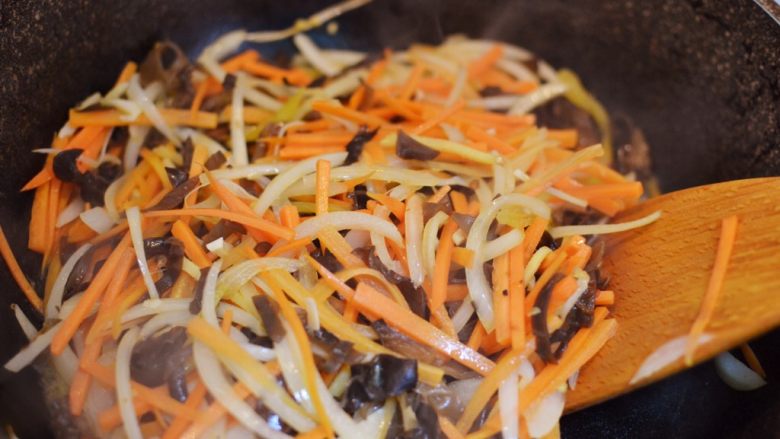 鱼香肉丝,放入胡萝卜丝、木耳丝和洋葱丝翻炒至食材变软。