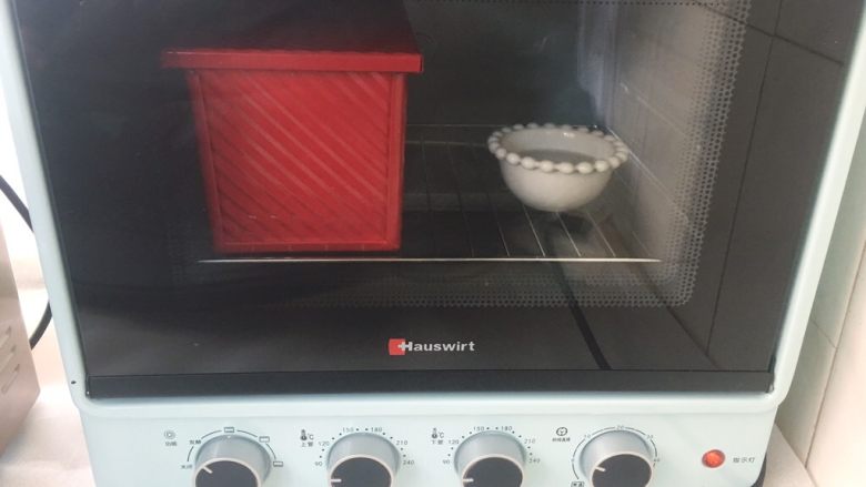 烫种吐司,烤箱放碗热水，将模具放入烤箱内，启动发酵程序二次发酵面团，我发酵了将近一个小时；
