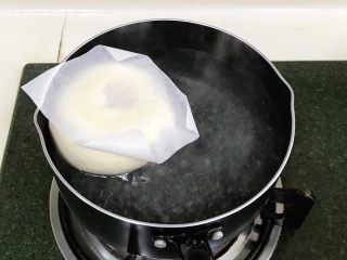 贝果汉堡包,取1升的水，加入50克细砂糖，烧至微沸状态后转小火，把面胚和油纸一起入糖水锅中煮。
