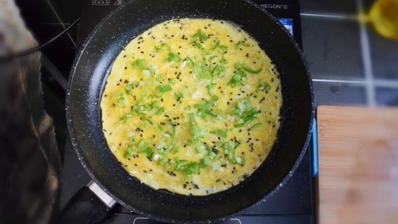 青椒虾皮鸡蛋卷,待蛋液煎成型后，撒上葱花和青椒。