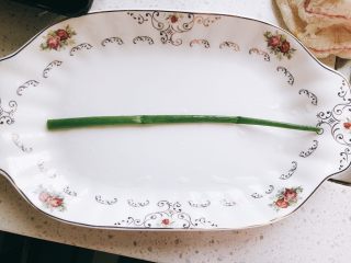 鞭炮迎春-年夜饭,取一根香葱，摆在盘子中间。