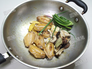 红烧鸡翅,加入香菇片、香葱结、生姜、大蒜炒出香味。