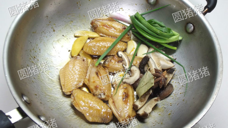 红烧鸡翅,加入香菇片、香葱结、生姜、大蒜炒出香味。