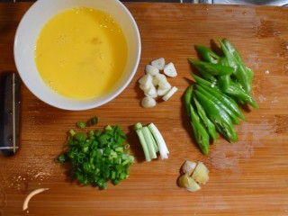 西兰花番茄炒鸡蛋盖浇饭,鸡蛋打入碗中，用筷子搅匀。葱切成葱段和葱花，姜和蒜切片，青椒去籽切片。